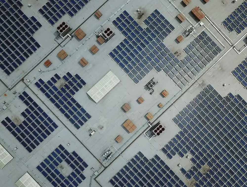 Aerial view of rows of solar panels on a flat commercial roof (illustrative photo)